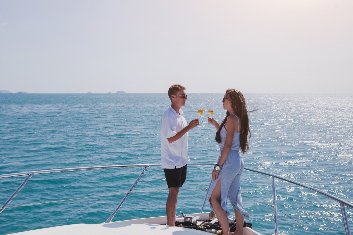 Couple standing at the bow drink wine.